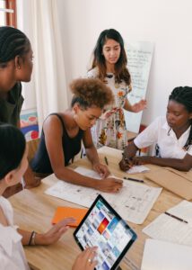 a group of women around a table work on a document together