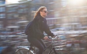 a woman speeds along a street on her bicycle