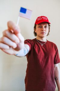 a kid in a MAGA hat holds up a flag