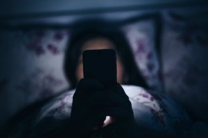 Woman reading and texting on smartphone in bed