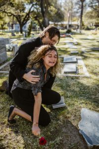 a mother and father grieve at a cemetery