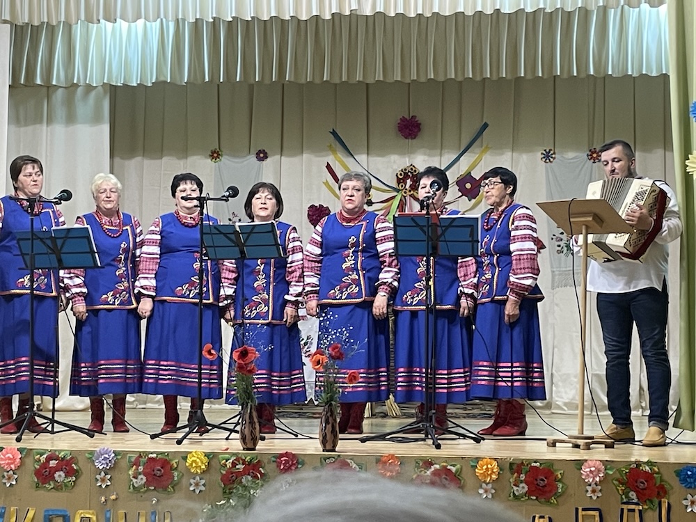 A group of women in traditional garb singing on stage