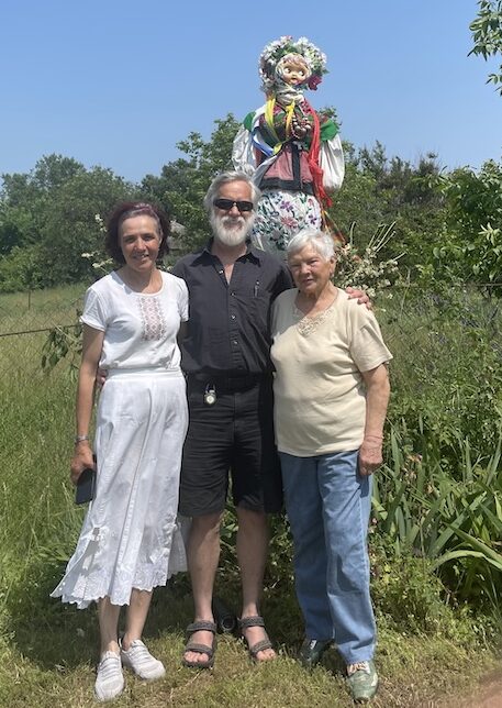 Three people stand next to a pagan effigy