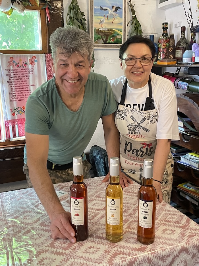 Two smiling faces with an offering of local wine